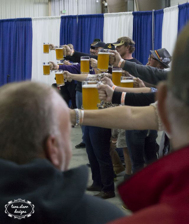 people holding beer glasses in the air in a line